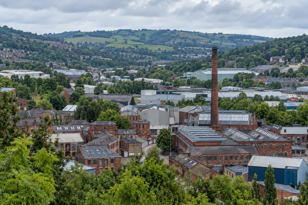 Northern industrial valley with brick workshops, factory roofs and green hills